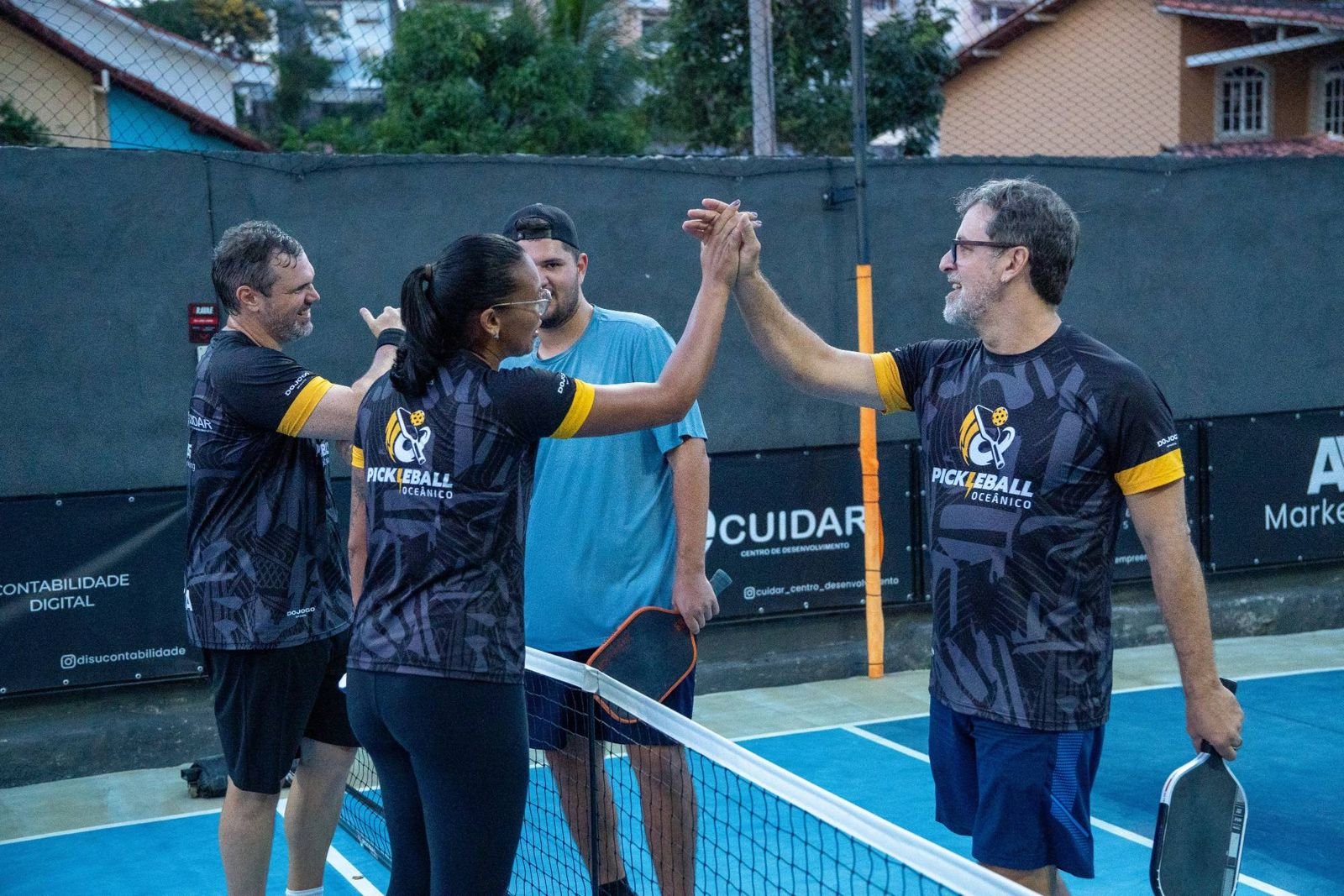 Alunos adultos da turma batendo as mãos na rede depois do jogo
